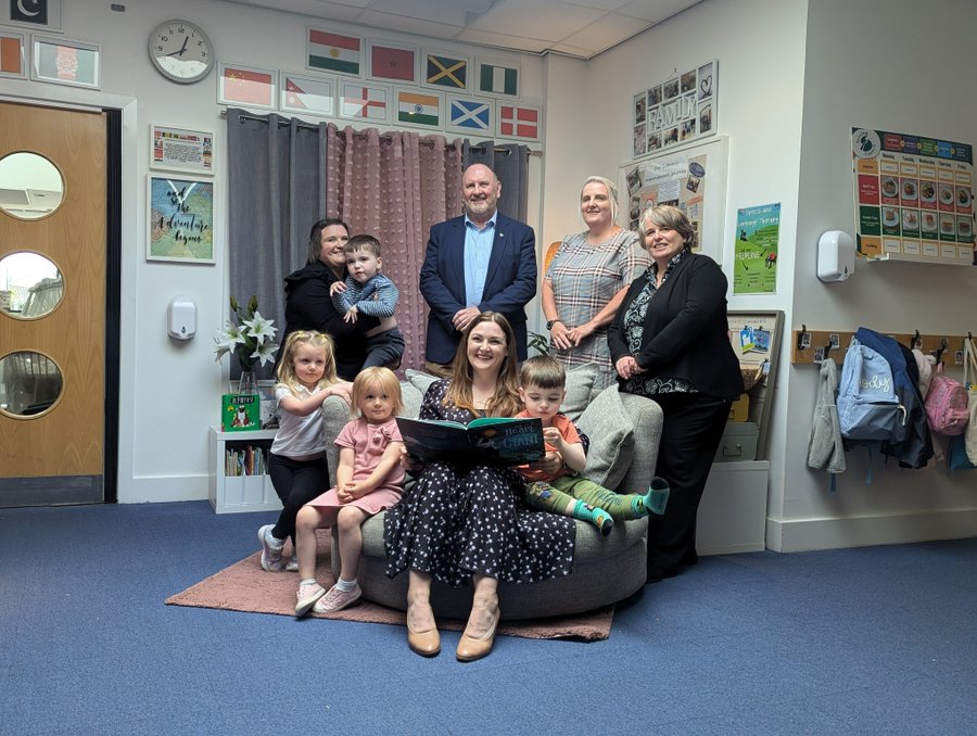 A group of people smiling. They are in a nursery setting.